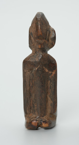 drewniana figura - Ujęcie z tyłu. Drewniana, rzeźbiona figura. Twarz ledwie zaznaczona, tułów prosty, dobrze zaznaczone piersi, stopy zaznaczone symbolicznie.