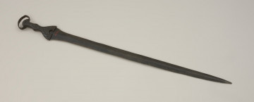broń - Ujęcie tyłu miecza. Brązowy miecz posiada czworokątną rękojeść z nerkowatym pałąkiem oraz dzwonowaty jelec.
