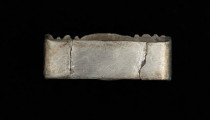Szlufka do pendentu księcia Kazimierza VI/IX (1557-1605) - Ujęcie z tyłu. Prostokątna szlufka wykonana z gładkiej, srebrnej taśmy, z ozdobnie opracowaną częścią przednią w formie tralki, pokrytą grawerowaną i niellowaną dekoracją.