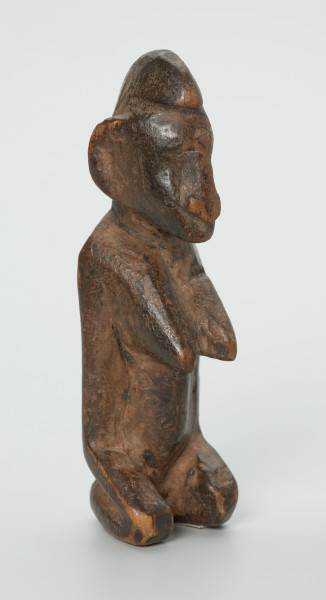 drewniana figura - Ujęcie z przodu skosem w prawą stronę. Drewniana, rzeźbiona figura. Twarz ledwie zaznaczona, tułów prosty, dobrze zaznaczone piersi, stopy zaznaczone symbolicznie.