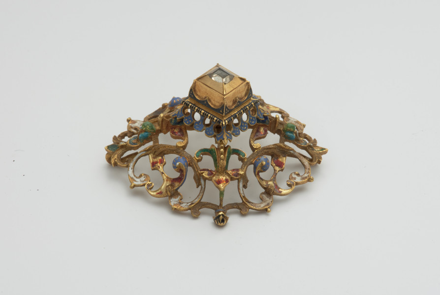 biżuteria, ozdoby - Ujęcie z boku z lewej strony. Ażurowy klejnot z kołpaka z diamentem, zdobiony barwną emalią.