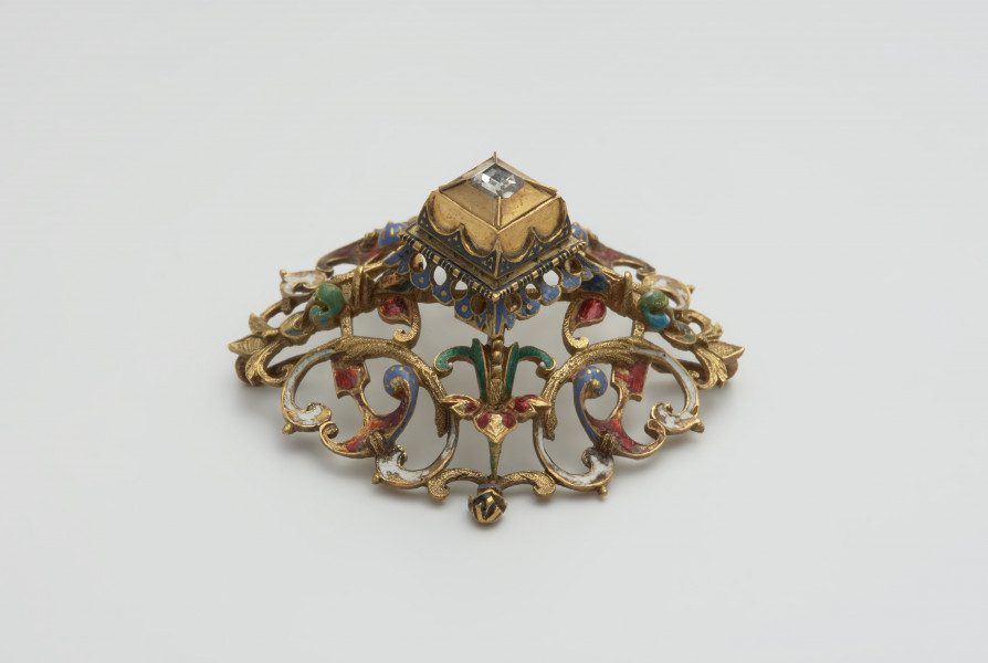 biżuteria, ozdoby - Ujęcie z boku. Ażurowy klejnot z kołpaka z diamentem, zdobiony barwną emalią.