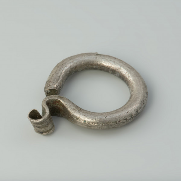 kabłączek skroniowy, biżuteria - Ujęcie przodu skosem w lewą stronę. Kabłączek skroniowy wykonany z srebrnego drutu o okrągłym przekroju z esowatym uszkiem.