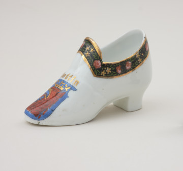 porcelanowy bucik ozdobiony malowanym szlaczkiem - Ujęcie przodu skosem w lewą stronę. Porcelonowy bucik ozdobiony malowanym szlaczkiem.
