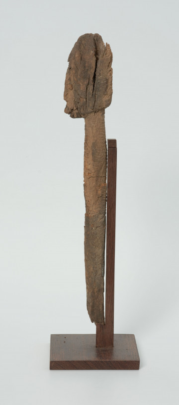 Ujęcie z prawego boku; Rzeźba. Figura - Nommo - drewniana pałka zakończona głową o cechach antropomorficznych. Widoczne spekania na glowie.