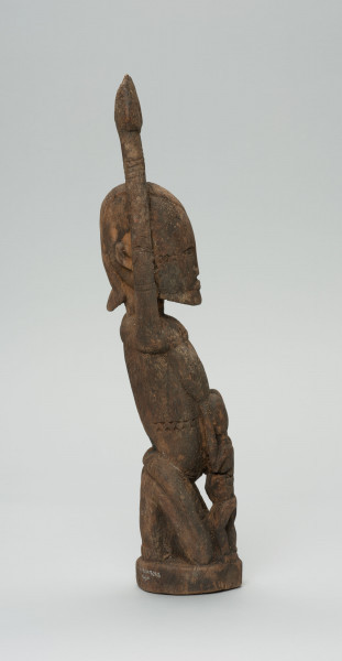 rzeźba - Ujęcie z lewego boku; Kobieta przedstawiona w pozycji klęczącej z rękoma uniesionymi do góry. Karmi dzieci (bliźnięta) dzieci ukazane od tyłu.