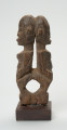 rzeźba - Ujęcie lewego boku. Wizerunek dwóch mitycznych postaci Yebane. Stykają się od tyłu głowami, pośladkami.