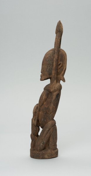 rzeźba - Ujęcie z prawego boku; Kobieta przedstawiona w pozycji klęczącej z rękoma uniesionymi do góry. Karmi dzieci (bliźnięta) dzieci ukazane od tyłu.