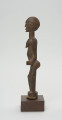 rzeźba - Ujęcie z prawego boku; Figura - postać kobiety w pozycji stojącej. Głowa mała, podłużna, ręce, piersi, brzuch lekko wydobyte z bryły figury. Nogi bez stóp, przechodzą od razu w okrągły cokolik.