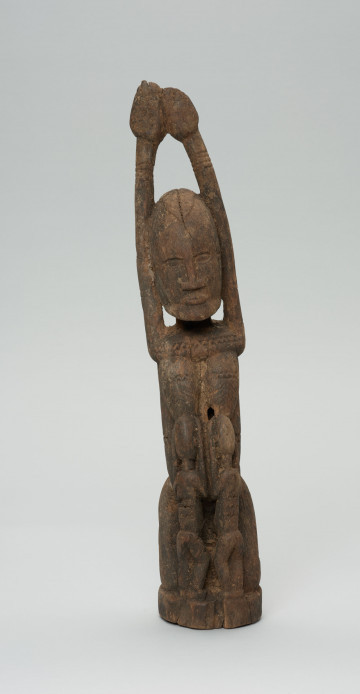 rzeźba - Ujęcie z przodu; Kobieta przedstawiona w pozycji klęczącej z rękoma uniesionymi do góry. Karmi dzieci (bliźnięta) z piersi, dzieci ukazane od tyłu.