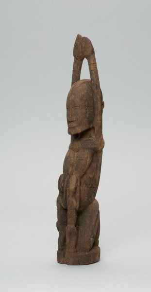 rzeźba - Ujęcie przodu i boku z prawej; Kobieta przedstawiona w pozycji klęczącej z rękoma uniesionymi o góry. Karmi dzieci (bliźnięta)z piersi, dzieci ukazane od tyłu. Rzeźba na całym ciele zdobiona szlaczkami.