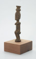 rzeźba - Ujęcie ze skosu z prawej; Figura - postać kobiety. Figura w pozycji siedzącej. Na głowie naczynie, twarz płaska, uwydatnione piersi oraz pępek.