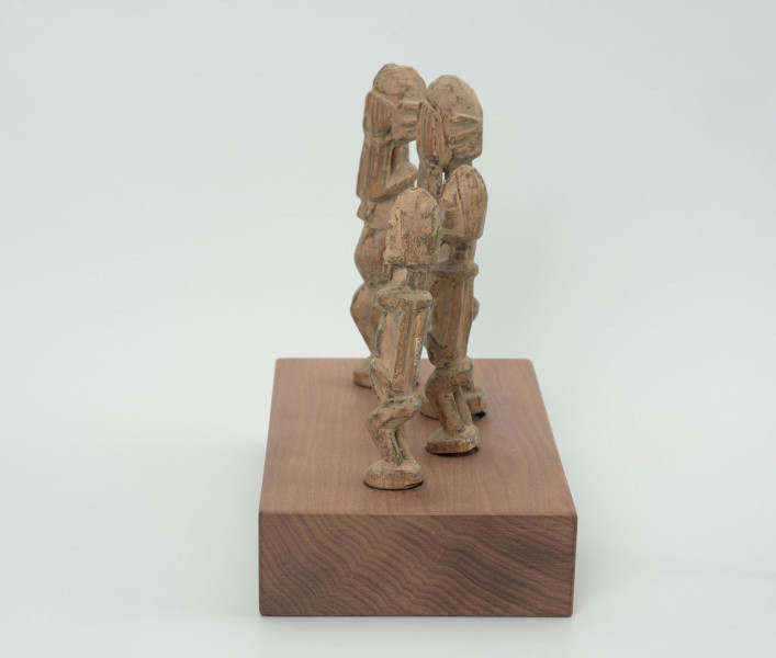 rzeźba - Ujęcie z boku; Zestaw składa się z czterech jasnych, drewnianych figurek przedstawiających postacie ludzkie w pozycji stojące – jedna para mniejsza, a druga większa. Większa para ma zakryte dłońmi oczy.