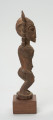 rzeźba - Ujęcie lewej strony. Figura mężczyzny w pozycji stojącej (na ugiętych w kolanach nogach) z rękoma uniesionymi do góry. Cała powierzchnia rzeźby pokryta jest delikatnym rytem, sugerującym skaryfikację.