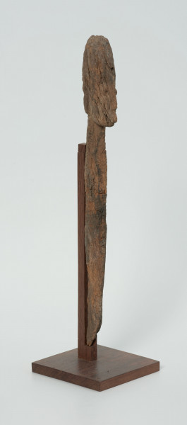 Ujęcie z skosu z lewej; Rzeźba. Figura - Nommo - drewniana pałka zakończona głową o cechach antropomorficznych. Spękania na całej głowie.