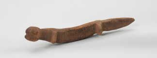 rzeźba - Ujęcie z przodu z lewej strony. Figurka przedstawia ayo geu – krokodyla krótkopyskiego. Wizerunek krokodyla uproszczony, na całęj powierzchni pokryty płytkimi nacięciami.