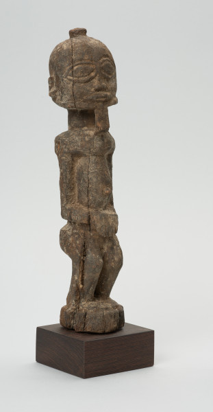 rzeźba - Ujęcie z przodu z prawej strony. Figura przedstawiająca mężczyznę stojącego na nogach ugiętych w kolanach. Głowa duża, zaokrąglona, oczy duże, ze źrenicami, wyraźnie zaznaczona bródka.