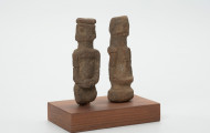 rzeźba - Ujęcie z lewego boku; Zestaw składa się z dwóch małych, drewnianych figurek przedstawiających postacie ludzkie w pozycji stojącej. Rzeźby o uproszczonej formie i masywnej budowie ciała.