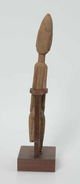 drewniana, rzeźbiona figura - Ujęcie z tyłu. Drewniana, rzeźbiona figura smukłej postaci znajdującej się w pozycji siedzącej. Długa broda ciągnąca się aż do kolan. Prawa dłoń spoczywa na kolanie, lewa trzyma brodę.