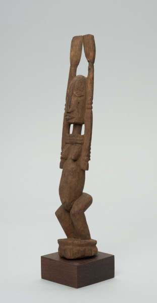 rzeźba - Ujęcie z przodu z lewej strony. Figura przedstawiajaąca postać kobiety z rękoma uniesionymi do góry. Ręce są nie proporcjonalnie długie.