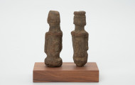 rzeźba - Ujęcie z tyłu; Zestaw składa się z dwóch małych, drewnianych figurek przedstawiających postacie ludzkie w pozycji stojącej. Rzeźby o uproszczonej formie i masywnej budowie ciała.