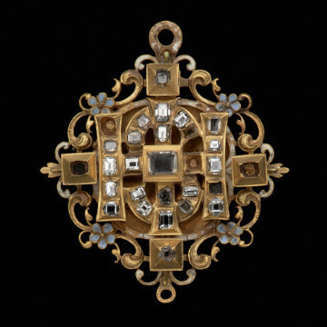 Wisior z liter IHS księcia Franciszka I (1577-1620) - Ujęcie z przodu. Wisior ze splecionych liter IHS, kameryzowanych diamentami, umieszczonych na ażurowej, zdobionej emalią podstawie. Klejnot ma dwupoziomową strukturę. Dolny stelaż zbudowany jest z okrągłej plakietki otoczonej ażurem z motywem wolut i kwiatów niezapominajek, z dwoma okrągłymi uszkami: większym do zawieszania klejnotu oraz mniejszym do podwieszania perły. Górną część tworzy kompozycja z diamentów o szlifie tablicowym w kasetowych oprawach. Obie części połączone są śrubami.