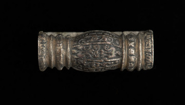 Szlufka do pendentu księcia Kazimierza VI/IX (1557-1605) - Ujęcie z przodu. Prostokątna szlufka wykonana z gładkiej, srebrnej taśmy, z ozdobnie opracowaną częścią przednią w formie tralki, pokrytą grawerowaną i niellowaną dekoracją.