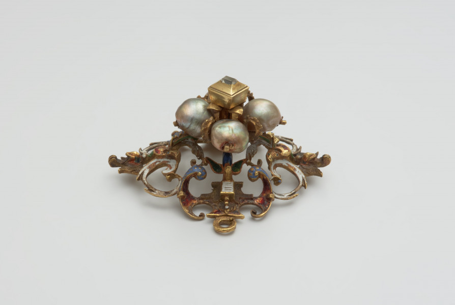 biżuteria, ozdoby - Ujęcie z boku od góry. Ażurowy klejnot z kołpaka z diamentem i czterema perłami, zdobiony barwną emalią.