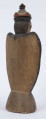 E/8100/ML - Rzeźba pełna wykonana z jednego kawałka drewna lipowego, polichromowana. Postać w hieratycznej postaci, w układzie frontalnym. Ręce wsparte na biodrach. Postać stoi na stożkowatym cokole. Na głowie korona z dwóch oddzielnych kawałków drewna, złączonych ozdobnym czopem drewnianym. Włosy czarne, ręce i twarz różowa, korona żółta z czerwonym obrzeżem, zwieńczenie czarne. Płaszcz stylizowany, przypominający skrzydła lub ornat, czarny. Szaty wewnętrzne żółte z czerwonymi plamkami. Wewnątrz długie, zielone z niebieskimi plamami. Buty czarne. Na piersiach duże otwarte serce zwieńczone czarnym krzyżem. Cokół w naturalnym kolorze drewna, ozdobiony pionowymi niebieskimi paskami i czerwonymi kropkami. Wym. cokołu: 13 x 10,5 cm. Sygnatura na spodzie (pisana): Jan Kaproń.