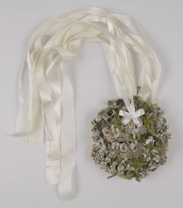 E/527/ML - Strój głowy w formie wianka. Na konstrukcji z drutu napięte są białe płócienne kwiaty, zielone listki oraz przypiete sa białe wstążki. Wianek noszony przez panny młode.
