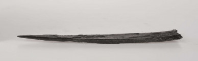 Miecz żelazny, jednosieczny, rytualnie zgięty. W górnej części głowni zdobienie ornamentem geometrycznym, typ D/2 wg Biborskiego.