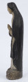 E/6363/ML - Rzeźba z drewna lipowego, polichromowana farbą olejną. Zakomponowana w jednym kawałku drewna na postumencie o formie owalnej z płaskorzeźbionym motywem dwóch skrzyżowanych gałęzi. Postać stojąca przedstawia Matkę Boską Różańcową. Twarz owalna, głęboko osadzone oczy, prosty i szeroki nos, małe pełne usta. Ręce zgięte w łokciach: duże dłonie złożone do modlitwy. Na przedramieniu prawej ręki brązowy różaniec o płaskich paciorkach, zakończony dużym krzyżem. Postać odziana w białą prostą suknię, gładko wykończoną pod szyją i przewiązaną granatową szarfą. Na głowie granatowa szata spełniająca jednocześnie rolę peleryny spływającej z ramion ku dołowi i spowijającej całą postać.