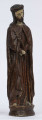 E/6362/ML - Rzeźba z drewna lipowego, polichromowana farbą olejną. Przedstawia postać Chrystusa. Na nieregularnej owalnej podstawie, o wym. 8,5 x 10,5 cm, wys. 3,5 cm, zakomponowana postać stojącego Chrystusa. Postać w długiej sukni, ułożonej w fałdy. Ręce, małe, złożone na brzuchu. W prawej trzyma liść palmy. Na ramionach narzucony płaszcz. Suknia i płaszcz pomalowane na wiśniowo-brązowy kolor. Twarz wydłużona, o wyrazistych rysach. Nos prosty. Oczy zamknięte. Pod nosem wąsy i broda. Twarz, ręce i widoczne spod sukni bose stopy, pomalowane farbą kremową. A głowie brązowe włosy opadające na ramiona, zaczesane z przedziałkiem pośrodku oraz cierniowa korona z wałeczkowatych elementów.