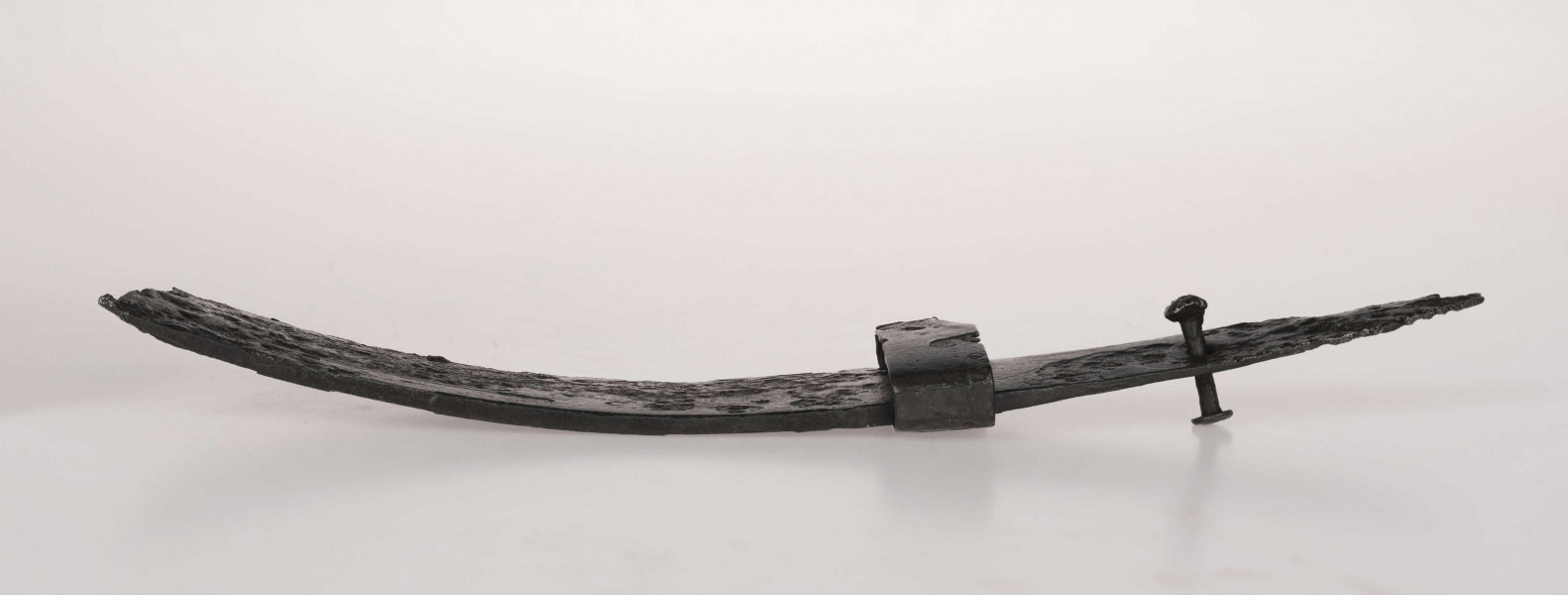 Miecz żelazny, jednosieczny, rytualnie zgięty. W górnej części głowni zdobienie ornamentem geometrycznym, typ D/2 wg Biborskiego.