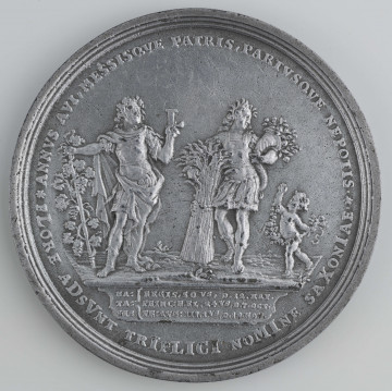 N/1557/ML - AV. Z lewej postać króla w rzymskim stroju z cyfrą L w lewej ręce. Obok, z prawej postać młodzieńca opartego o snopek z boża, z rogiem obfitości. Obok dziecko z girlandą. W otoku napis: (zob. w zakładce 