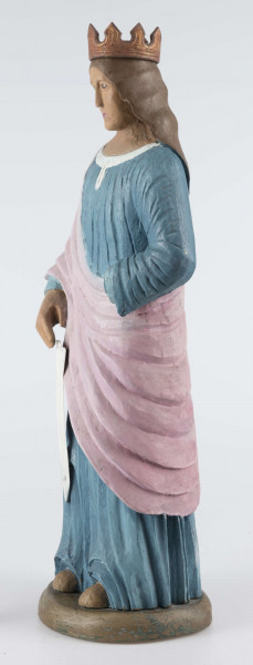 E/16790/ML - Rzeźba drewniana pełna polichromowana, przedstawiająca św. Katarzynę. Postać stojąca, ubrana w niebieską (wcześniej kolor ultramaryny) suknię, żłobioną  w fałdy, z białym wykończeniem przy szyi. Na wierzch, na prawe ramię, narzucony płaszcz/szal w kolorze jasnoróżowym. Prawa ręka opuszczona, trzyma miecz (obecnie samo ostrze koloru białego), lewa zgięta jest w łokciu – brak partii dłoni. Odsłonięte części ciała (stopy, dłonie, szyja, twarz) w kolorze jasnobrązowym; wcześniej prawdopodobnie beżowo-kremowe. Twarz owalna, brązowo-błękitne gałki oczne, usta różowe. Włosy brązowe, spływające fałdami do połowy pleców. Na głowie korona z 8 wierzchołkami, żłobiona, brązowa, uszlachetniona złotą farbą. 
Postać stoi na owalnej podstawie (22 x 19 cm), o wys. 3,5 cm, pomalowanej na brązowo (umbra), wcześniej – w szmaragdowej zieleni.