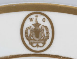 S/CS/1362/1/ML - Talerz płytki, okrągły, gładki, biały, kołnierzujety w dwa złote paski, na kołnierzu złoty owalny medalion z herbem Pomian i monogramem rozdzielonym W O.
Na spodzie sygnatura malowana czerwienią:
 