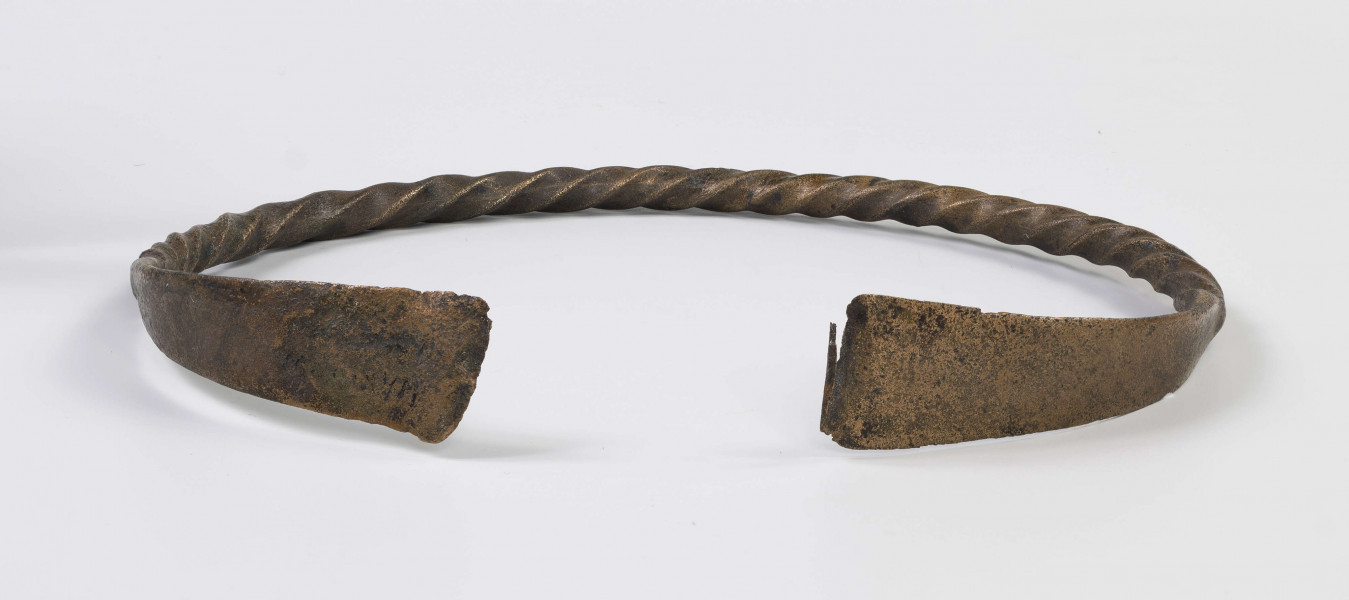 1396/A/ML/4 - Naszyjnik brązowy wykonany z czworograniastego pręta skręconego dookoła swej osi. Oba kóńce naszyjnika spłaszczone i nadkruszone. Naszyjnik bardzo silnie wytarty od dłuższego używania. 