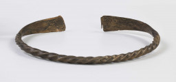1396/A/ML/4 - Naszyjnik brązowy wykonany z czworograniastego pręta skręconego dookoła swej osi. Oba kóńce naszyjnika spłaszczone i nadkruszone. Naszyjnik bardzo silnie wytarty od dłuższego używania. 