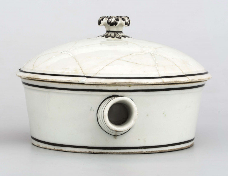 Naczynie stożkowate z uchwytem w postaci szerokiej rurki (służącym do zamocowania drewnianej rączki), pokrywa kopulasta z uchwytem w kształcie rozkwitłej korony kwiatowej. Krawędzie obwiedzione czarnymi paskami, czernią podkreślony modelunek uchwytu. Spód nieszkliwiony.
 