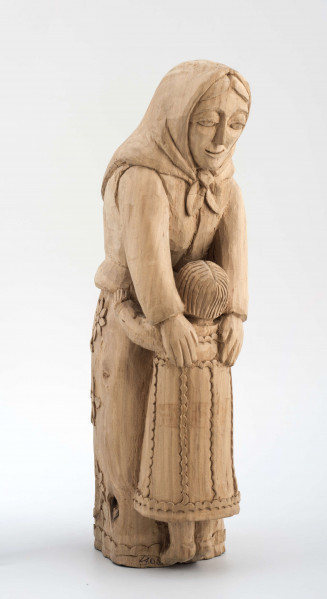 Rzeźba w drewnie lipowym, niepolichromowana, przedstawiająca postać kobiety nachylonej nad dzieckiem, stojącym przy kolanach. Kobieta w chustce na głowie zawiązanej pod brodą, o twarzy trójkątnej, dużych oczach, wąskich ustach. Ubrana w bluzkę z długimi rękawami i serdak z zaznaczoną baskinką , w długiej spódnicy pokrytej stylizowanymi wielopłatkowymi kwiatami na gałązce. U dołu biegnie pasek w formie falistej linii. Kobieta obejmuje rękami dziecko, zwrócone do niej twarzą. Dziecko z włosami sięgającymi do szyi, zaznaczonymi rowkowanymi nacięciami – uczesane z przedziałkiem  pośrodku. W długiej sukience, ozdobionej falistymi liniami poziomymi u dołu i góry, pionowymi pośrodku. 