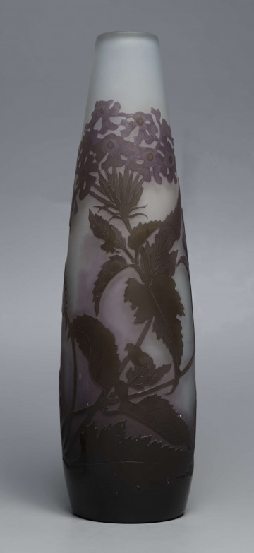 S/CS/1620/ML - Wazon o kształcie wrzecionowatym ze szkła grubościennego, matowego, bezbarwnego,  podbarwionego od dołu fioletem, od góry błękitem. Powlekany warstwą liliową i brązowooliwkową; w niej trawiona i polerowana dekoracja roślinna: swobodnie rozmieszczone gałązki werbeny z kwiatami.
 