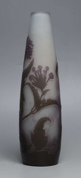 S/CS/1620/ML - Wazon o kształcie wrzecionowatym ze szkła grubościennego, matowego, bezbarwnego,  podbarwionego od dołu fioletem, od góry błękitem. Powlekany warstwą liliową i brązowooliwkową; w niej trawiona i polerowana dekoracja roślinna: swobodnie rozmieszczone gałązki werbeny z kwiatami.
 