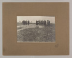 ML/H/F/26/6 - Fotografia przedstawia mężczyzn stojących w dwóch grupach. Po lewej cztery postaci, po prawej dziesięć. Kilku z nich trzyma kartkę papieru. W ziemi widać doły. Fotografia naklejona na brązową tekturę z wytłoczoną ramką. W prawym dolnym rogu pieczęć zakładu fotograficznego S. Zawadzkiego z Lublina.