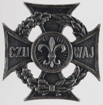 ML/MART/291 - Krzyż harcerski 4-ramienny wykonany z metalu, na środku lilijka harcerska, krzyż otaczają liście wawrzynu; napis na bocznych ramionach 