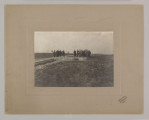 ML/H/F/26/8 - Fotografia przedstawia mężczyzn stojących w dwóch grupach. Po lewej cztery postaci, po prawej dziesięć. Kilku z nich trzyma kartkę papieru. W ziemi widać doły. Fotografia naklejona na szarą tekturę z wytłoczoną ramką. W prawym dolnym rogu pieczęć zakładu fotograficznego S. Zawadzkiego z Lublina. 