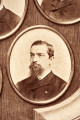 Pośrodku prostokątnego pola o zaokrąglonych narożnikach większa fotografia przyozdobiona wstęgą i gałązkami wawrzynu. Dookoła szesnaście symetrycznie rozmieszczonych mniejszych fotografii. W prawym górnym rogu dr Wacław Lasocki, naczelny lekarz kolei nadwiślańskiej w latach 1875 - 78. W polu ramy w górnej części medalion z płaskorzeźbionym popiersiem z profilu. Przedstawia Leopolda Kronenberga - ojca. Po bokach dwia półleżące aniołki trzymają wieniec laurowy. Po lewej stronie ramy postać robotnika Poleszuka, po prawej pracownika warsztatów kolejowych. W dolnej części front lokomotywy i złoty żeton uprawniający do bezpłatnej jazdy pociągiem I klasy. Fotografia naklejona na tekturę, w dolnej części u dołu sucha pieczęć zakładu fotograficznego.