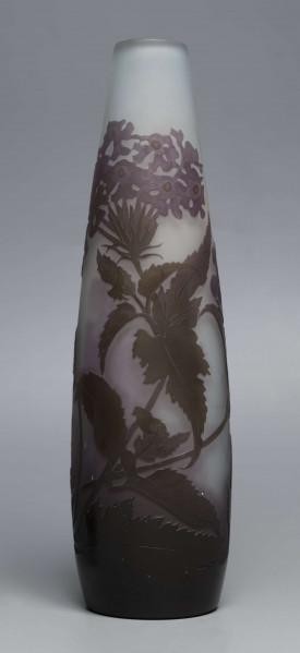 S/CS/1620/ML - Wazon o kształcie wrzecionowatym ze szkła grubościennego, matowego, bezbarwnego,  podbarwionego od dołu fioletem, od góry błękitem. Powlekany warstwą liliową i brązowooliwkową; w niej trawiona i polerowana dekoracja roślinna: swobodnie rozmieszczone gałązki werbeny z kwiatami.
 