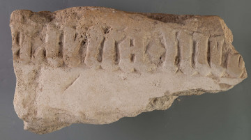 Fragmenty kamiennej płyty z wyrytym późnogotyckim napisem.