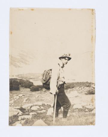 Zdjęcie Adama Żeromskiego w rynsztunku sportowym, z plecakiem, laską wśród kamieni i na tle gór. Na drugim planie widać kosodrzewine.